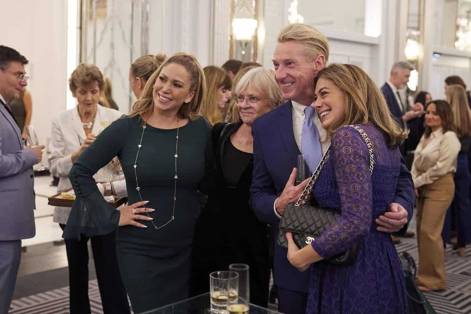 A group of well-dressed people, reminiscent of the British royal family, pose together at a social event in an elegant room.