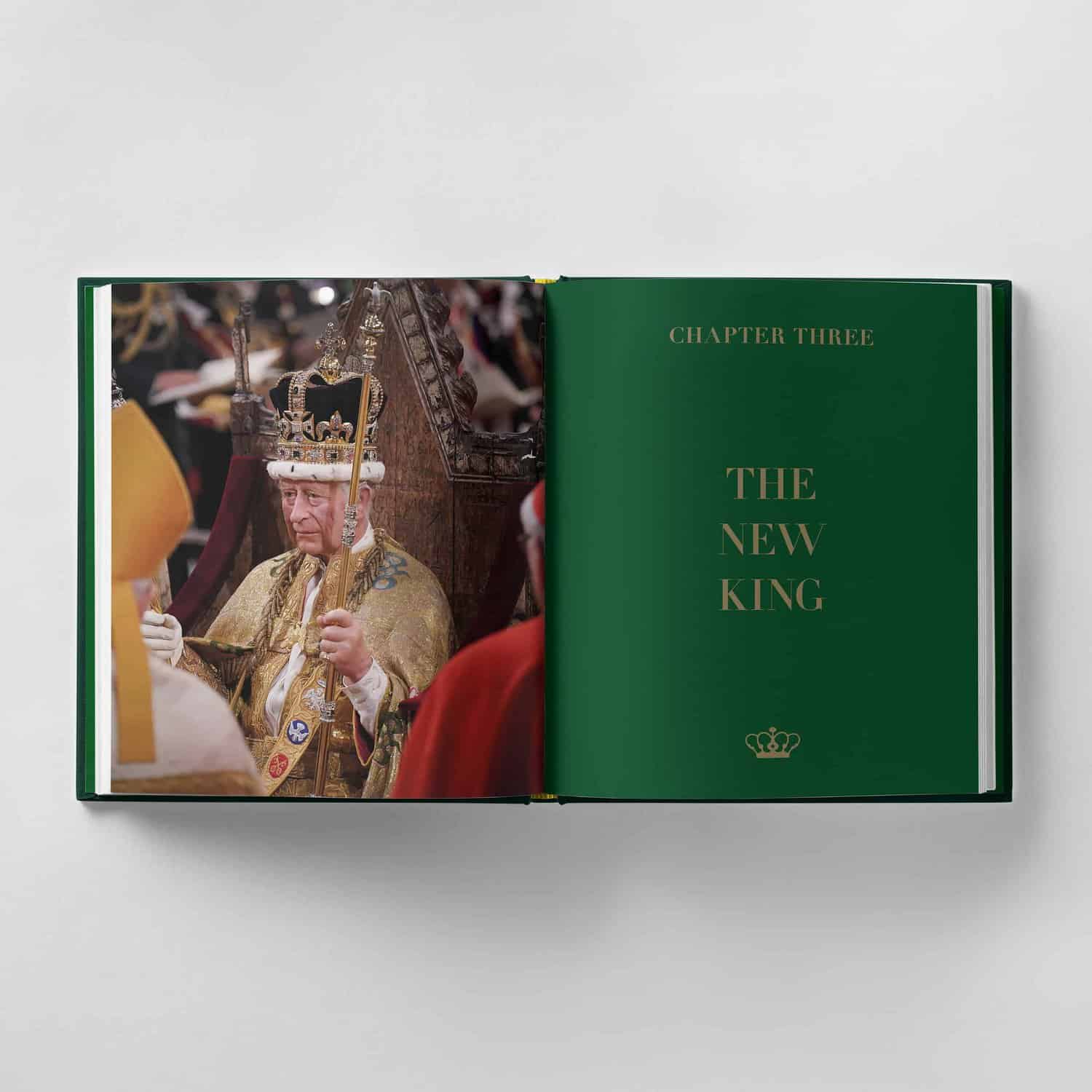 An open book reveals a photograph of King Charles III holding a scepter on the left page, while "Chapter Three: The New King" is elegantly displayed in green text on the right page.