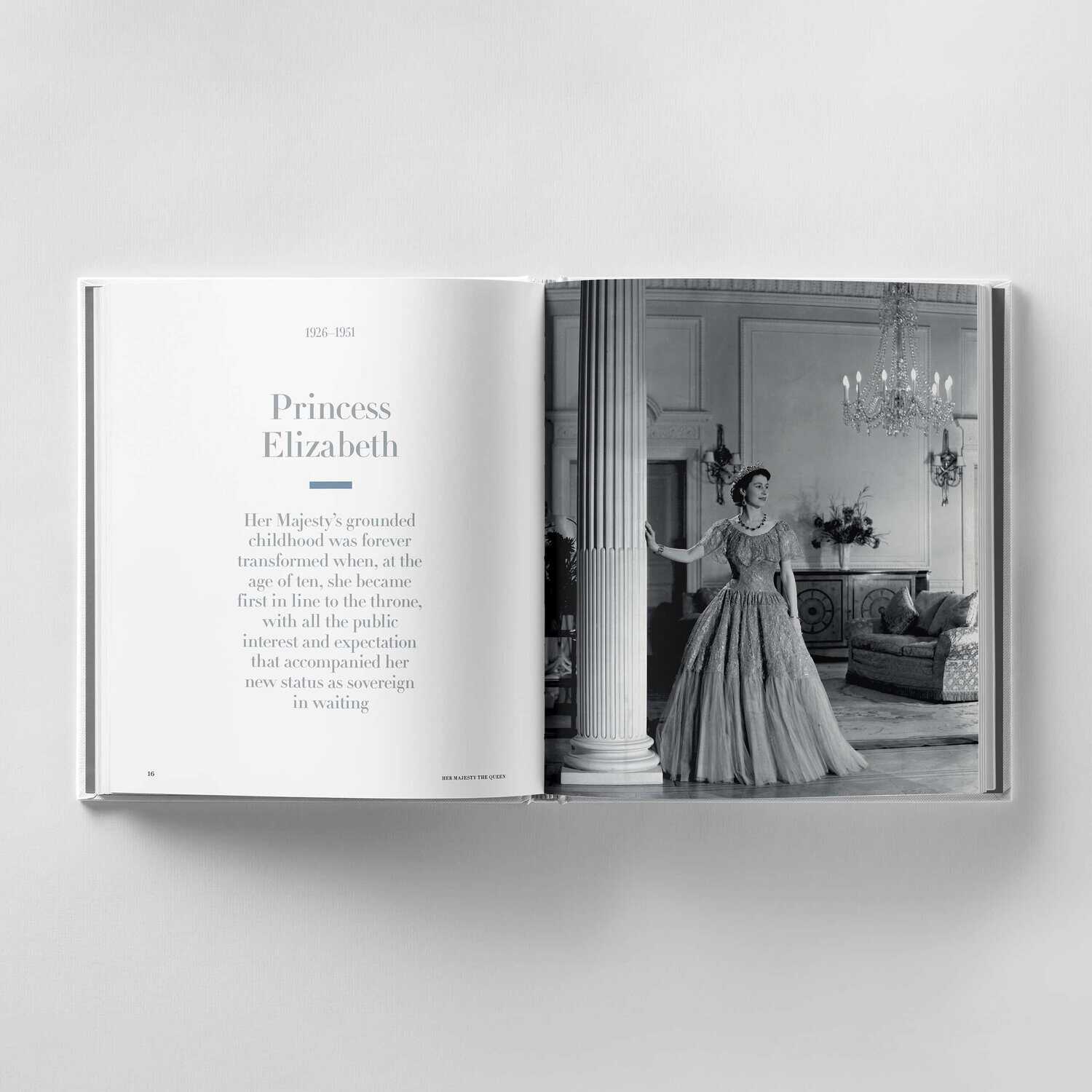 The open book reveals a left page with text about Princess Elizabeth, hinting at her future as Queen, while the right page displays a black-and-white photo of Her Majesty in a gown, standing gracefully in an ornate room befitting royalty.
