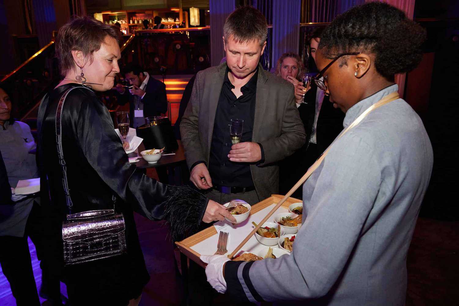 At the elegant Press Club Ball, attendees in formal attire gracefully selected food from a tray at the sophisticated social event.