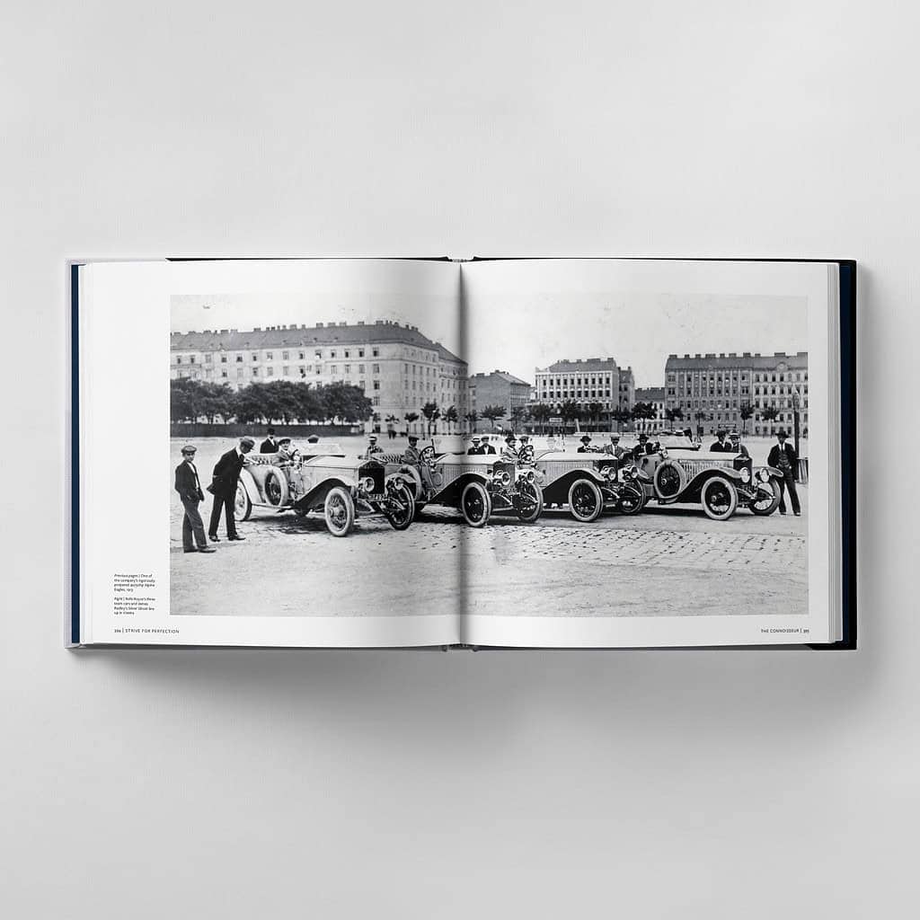 Open book displaying a vintage black-and-white photograph of several early 20th-century cars with people standing nearby, set against a backdrop of historic buildings and a cobblestone street, capturing a moment where craftsmanship and the pursuit of perfection met timeless style.