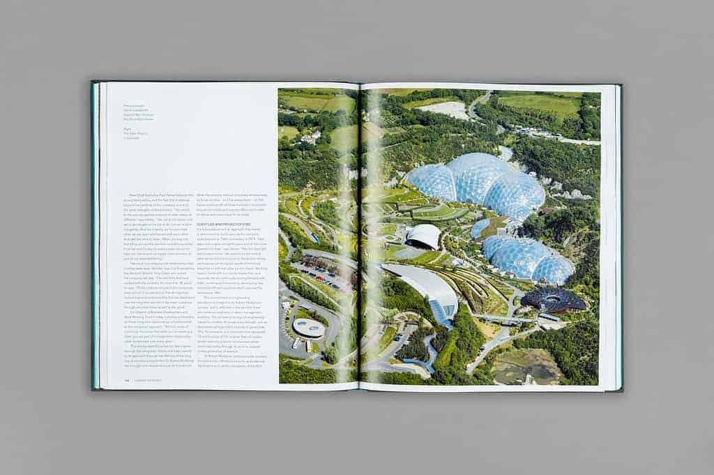 An open book reveals an aerial view of a botanical garden with multiple geodesic domes, highlighting nature's role in shaping the world. Lush greenery surrounds this scene, while text unfolds on the left page.