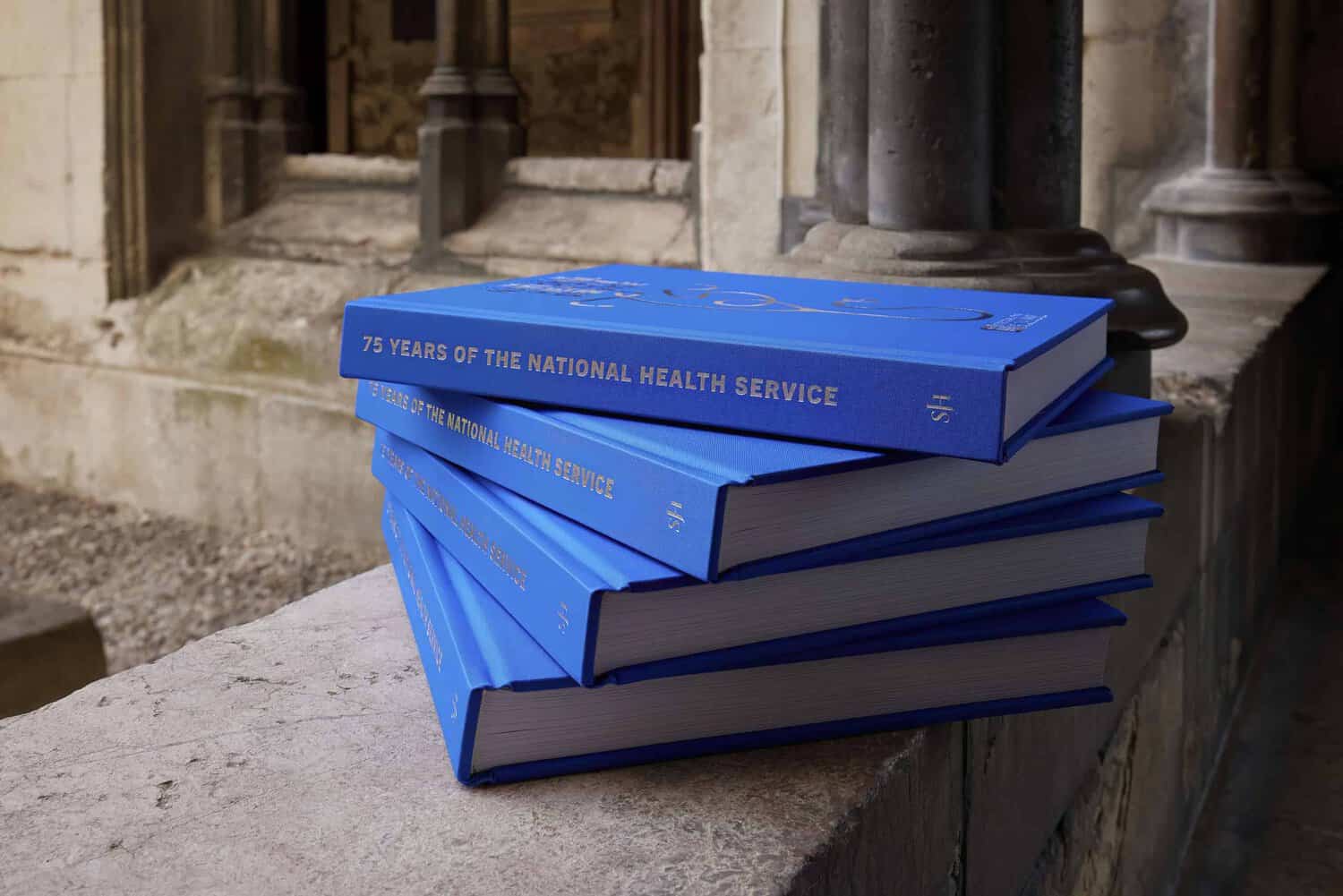 Four blue books titled "75 Years of the NHS" are neatly stacked on a stone ledge.